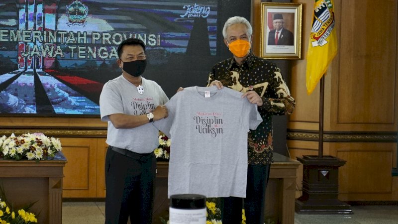 Moeldoko menerahkan kaus "Maskeran Den, Disiplin Niku Vaksin" kepada Gubernur Jawa Tengah, Ganjar Pranowo.
