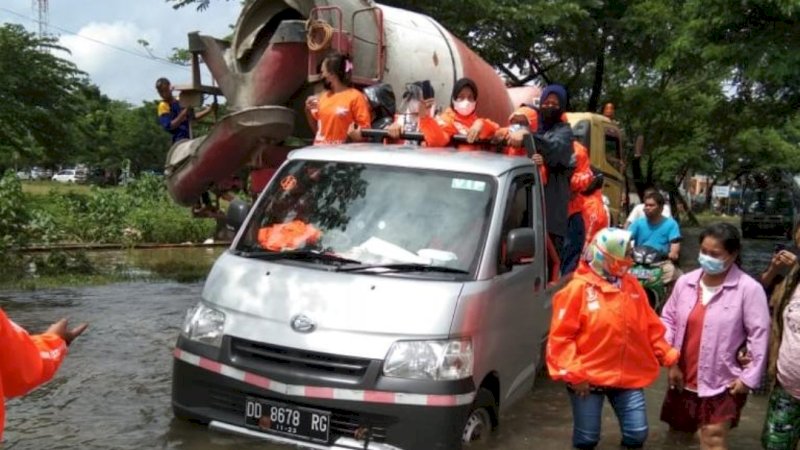 Para anggota komunitas Wero Ri Langi ADAMA' menembus banjir untuk menyerahkan bantuan. 