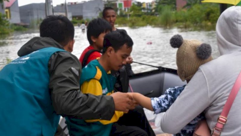 Relawan Wahdah Inspirasi Zakat saat mengevakuasi warga terdampak banjir.