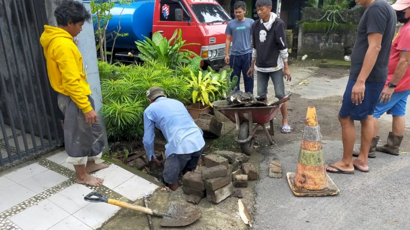 Petugas Tim Pelaksana Ruang Terbuka Hijau PDAM Makassar bersama warga sedang membersihkan drainase,  Sabtu, (13/3)