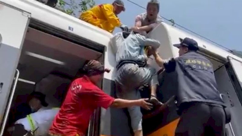 Seorang penumpang sedang dibantu naik ke atas kereta yang anjlok di terowongan Hualien, di bagian timur Taiwan, Jumat (2/4/2021). (Foto: hsnews.com.tw via AP)