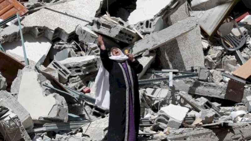 Perempuan berdiri di dekat puing-puing bangunan yang dihancurkan oleh serangan udara Israel di Gaza, Ahad (16/5/2021). (Foto: AP Photo/Adel Hana)