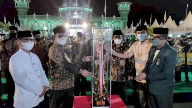 Pelaksana tugas Gubernur Sulsel, Andi Sudirman Sulaiman menyerahkan piala kepada kafilah Kota Makassar yang tampil sebagai juara umum. (Foto: Dok Pemprov Sulsel)