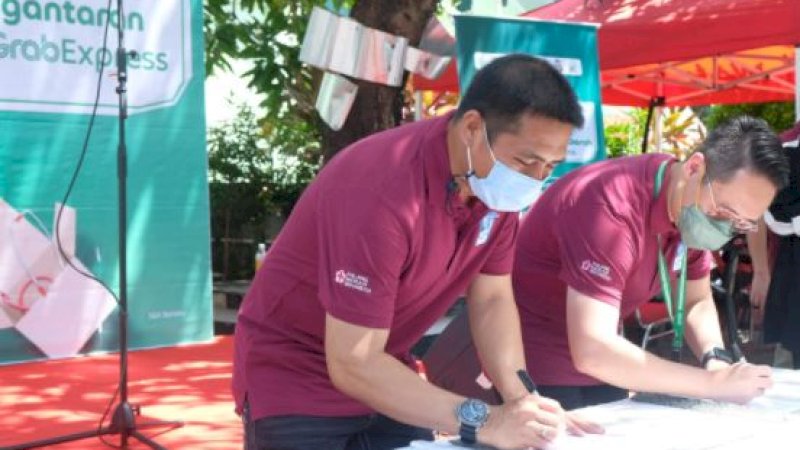 Ketua PMI Kota Makassar, Syamsu Rizal, bersama Director of East Indonesia, Grab Indonesia, Halim Wijaya, saat menandatangani kerja sama dalam menyediakan layanan pengantaran dokumen dan kantong darah bagi penerima donor darah melalui layanan kurir GrabExpress.