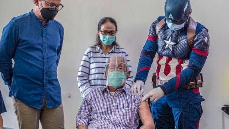 Wirjawan Hardjamulia disuntik oleh dokter Rollando Erric Manibuy yang berpakaian ala superhero. (Foto: Dinas Komunikasi dan Informatika Kota Bogor)