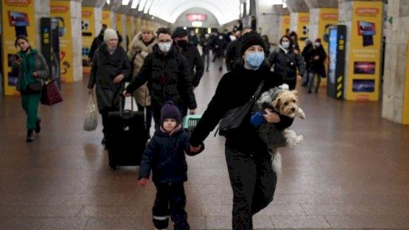 Seorang perempuan dengan seorang anak dan seekor anjing berjalan di stasiun metro di Kyiv, Kamis (24/2/2022). (Foto: AFP/Daniel Leal)