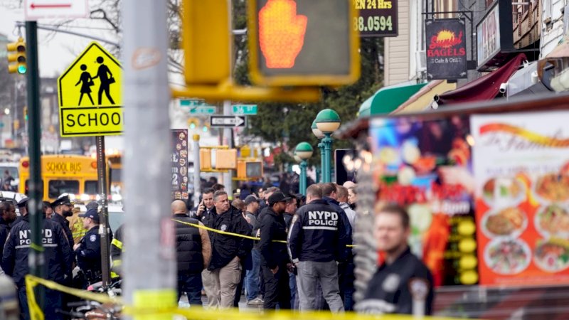 Polisi New York (NYPD) berkumpul di pintu masuk halte kereta bawah tanah di wilayah Brooklyn, New York, Selasa, 12 April 2022. Lima orang ditembak pria tak dikenal di sebuah stasiun kereta bawah tanah di Brooklyn, New York. (AP/John Minchillo)