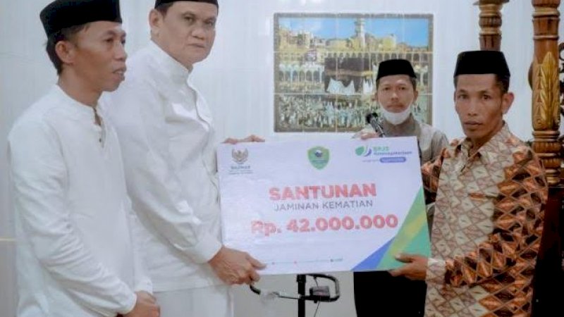 Bupati Barru, Suardi Saleh (kedua kiri) menyerahkan santunan kematian BPJS Ketenagakerjaan kepada ahli waris dari almarhum Dandu, imam Masjid Nurul Mannan.