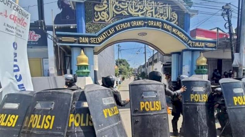 Polisi berjaga di depan gerbang Pondok Pesantren Shiddiqiyyah Ploso saat proses upaya penangkapan Moch Subchi Azal Tsani (MSAT) di Jombang, Jawa Timur, Kamis (7/7/2022). (Foto: Detik.com)