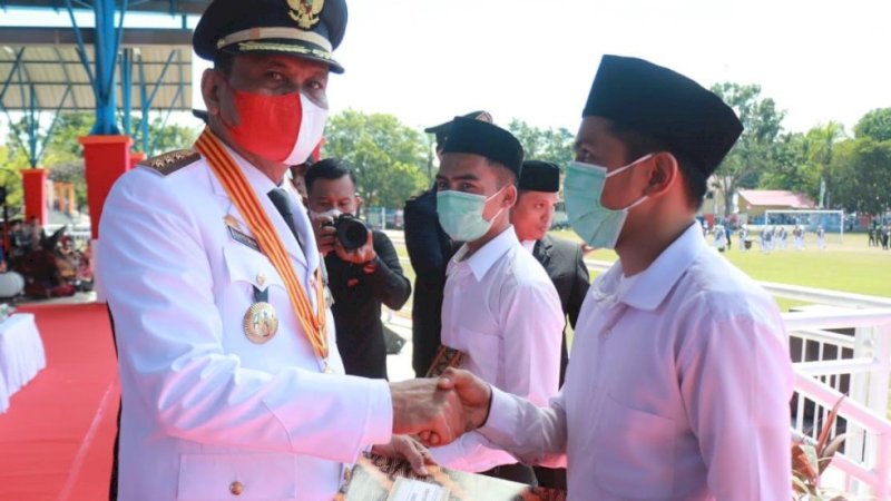 Bupati Barru, Suardi Saleh (kiri), menyerahkan langsung surat keputusan remisi tersebut kepada dua orang perwakilan warga binaan di panggung kehormatan.