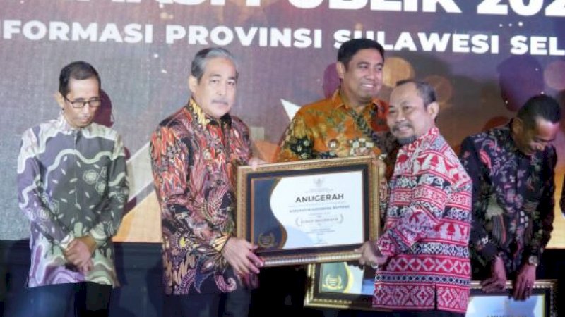 Bupati Sidrap, Dollah Mando (kiri), saat menerima penghargaan Anugerah Keterbukaan Informasi Publik 2022 dari KI Sulsel yang diserahkan Asisten III Bidang Administrasi, Tautoto Tana Ranggina, di Hotel Claro, Jalan A.P. Pettarani, Kota Makassar, Jumat (2/12/2022) malam. 