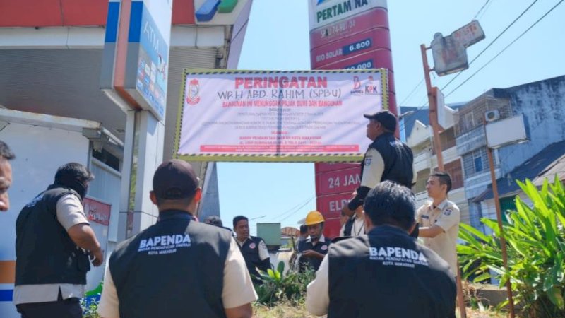 Tim penindakan Bapenda Makassar memasang spanduk atau stiker peringatan di lokasi SPBU yang menunggak PBB, Selasa (30/5/2023). (Foto: Humas Kominfo Makassar)