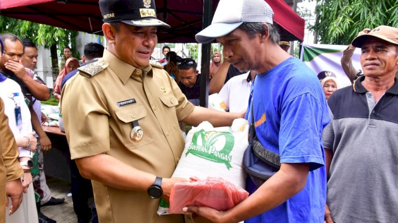 Penjabat (Pj) Gubernur Sulawesi Selatan (Sulsel), Bahtiar Baharuddin (kiri), saat menyerahkan bantuan pangan kepada salah satu penerima di halaman Kantor Camat Bantimurung, Maros, Sulsel, Selasa (30/1/2024). (Foto: Pemprov Sulsel)