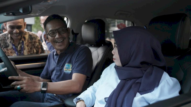 General Manager PLN UID Sulselrabar, Moch. Andy Adchaminoerdin (kiri) bersama Ketua PIKK PLN UID Sulselrabar, Rosmadewi (kanan) tengah mencoba mobil listrik di acara PLN Mobile Fun Fest 2024.