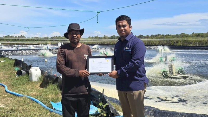 Penyerahan _Renewable Energy Certificate_ oleh Team Leader Pelayanan Pelanggan PLN Unit Layanan Pelanggan Takalar, Andy Mulya (kanan) kepada pemilik tambak udang vaname di Kabupaten Takalar, Sardi (kiri).