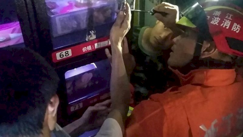 Petugas Pemadam Kebakaran Provinsi Zhejiang, menolong Zhu yang jarinya terperangkap di mesin penjual mainan seks.