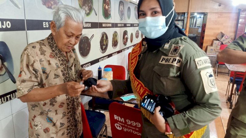 Duta Covid atau DPP Satpol PP Makassar membagikan masker kepada warga.